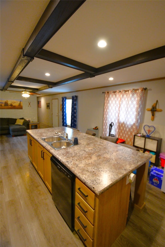 Kitchen featuring a center island with sink, beamed ceiling, light wood-type flooring, open floor plan, and dishwasher