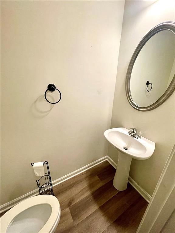 Bathroom featuring wood finished floors, baseboards, and toilet