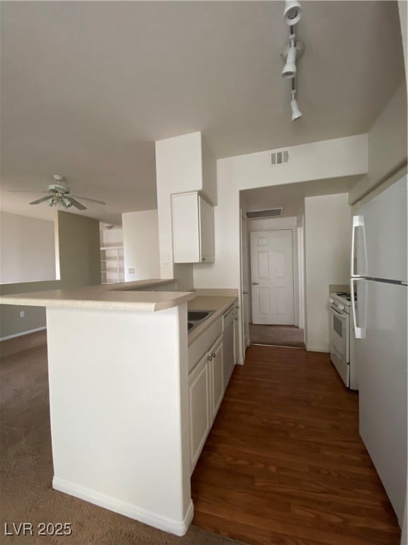 Kitchen with white cabinetry, fridge, white range oven, and a peninsula