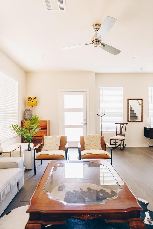 Living room featuring visible vents, a ceiling fa