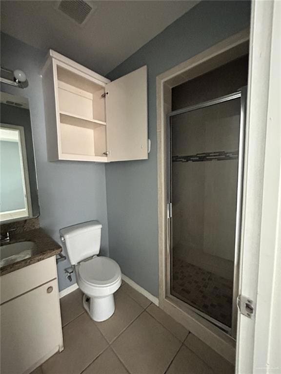 Bathroom with a stall shower, tile patterned floors, vanity, baseboards, and toilet