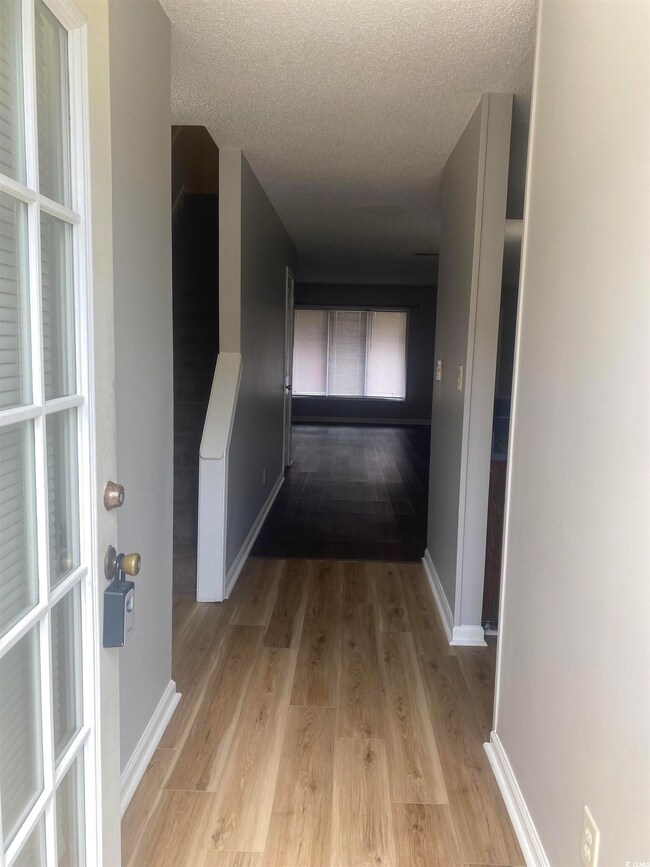Hall with light wood-style flooring and a textured ceiling
