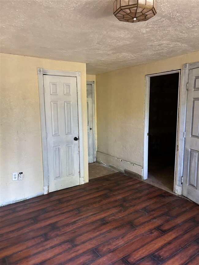 Empty room featuring a textured ceiling and dark hardwood / wood-style flooring