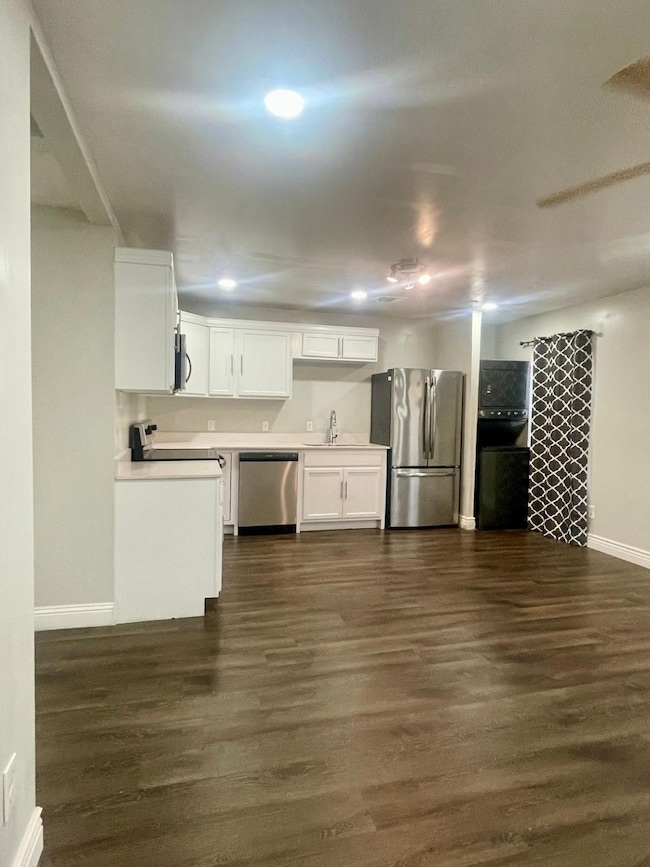 Kitchen featuring light countertops, white cabinetry, appliances with stainless steel finishes, and dark wood-type flooring