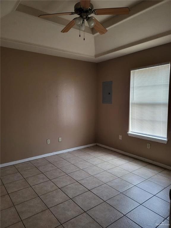 Empty room featuring light tile patterned flooring, a ceiling fan, electric panel, and a raised ceiling