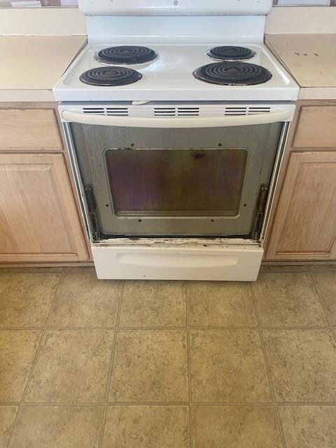 Details featuring light tile patterned flooring, light brown cabinets, and white electric stove