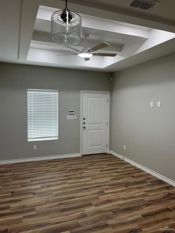 Entryway with ceiling fan, dark wood finished floors, baseboards, and a raised ceiling