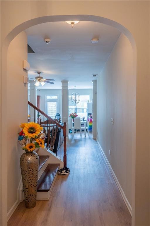 Corridor with wood finished floors, stairway, arch