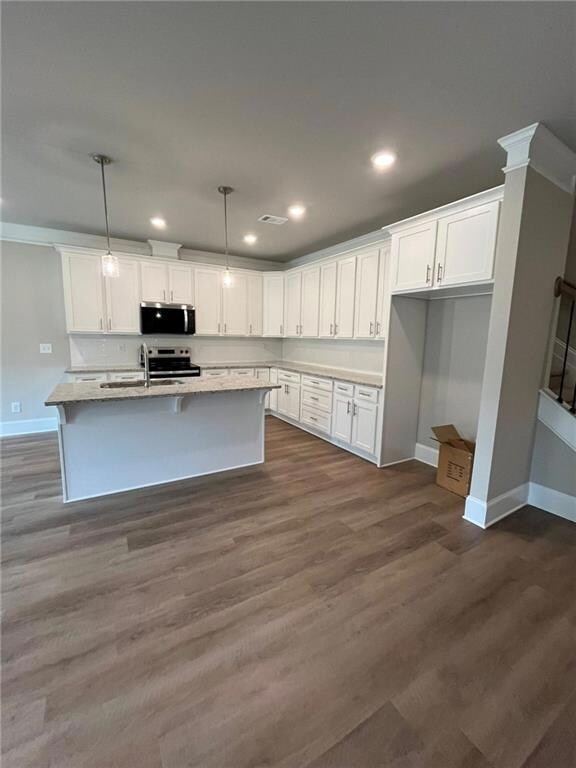 Kitchen with stainless steel appliances, white cabinets, recessed lighting, dark wood-style flooring, and decorative light fixtures