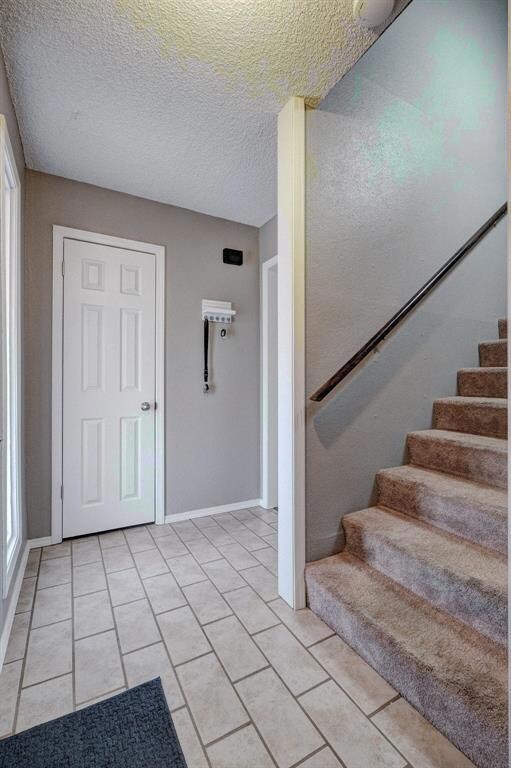 Foyer with light tile floors and a textured ceilin