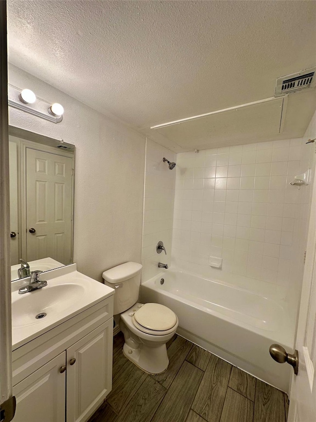 Full bathroom with visible vents, toilet, a textur