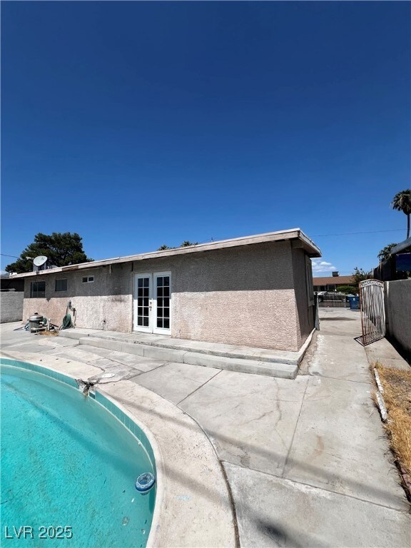 Back of house featuring stucco siding, a gate, and a patio