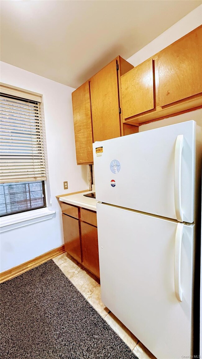 Kitchen featuring freestanding refrigerator, light countertops, brown cabinets, and light tile patterned flooring