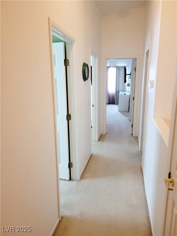 Corridor with light colored carpet and baseboards