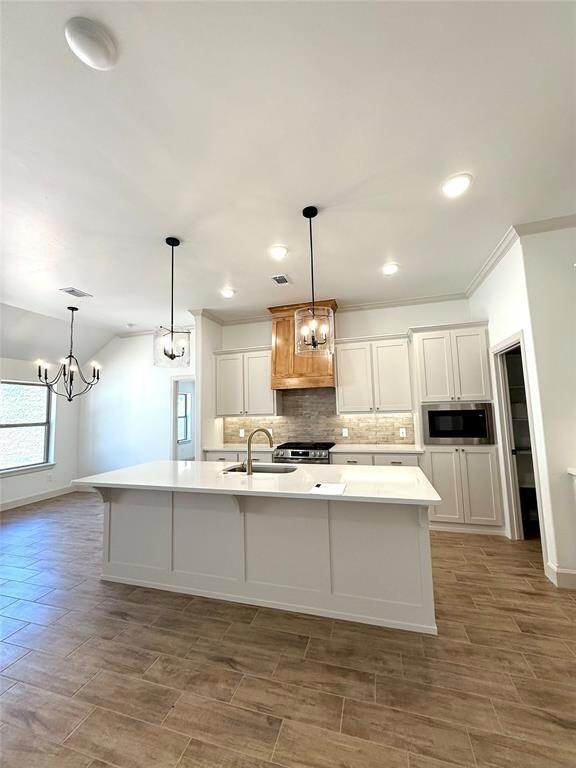 Kitchen with a sink, a chandelier, appliances with stainless steel finishes, tasteful backsplash, and light countertops