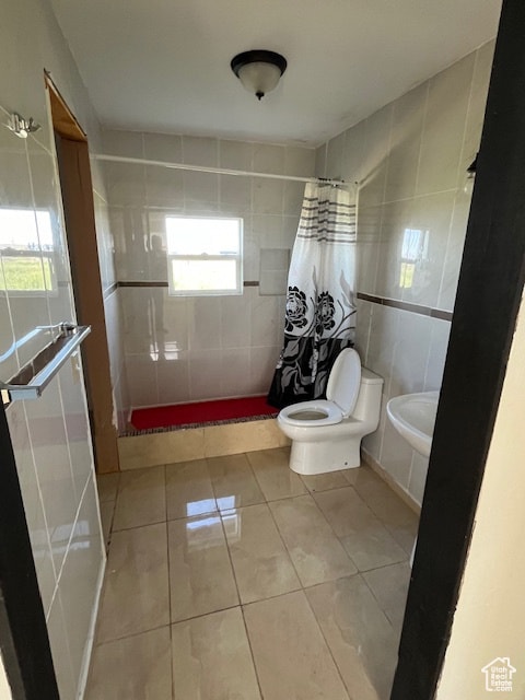 Bathroom featuring tile walls, light tile patterned floors, and a stall shower
