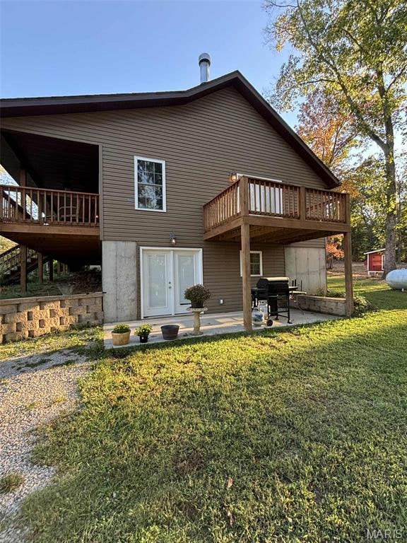 Back of house featuring a patio area, a wooden deck, and a lawn