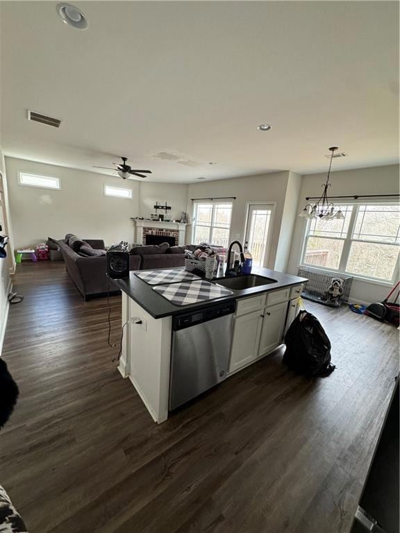 Kitchen with dishwasher, dark countertops, a brick fireplace, open floor plan, and dark wood-type flooring