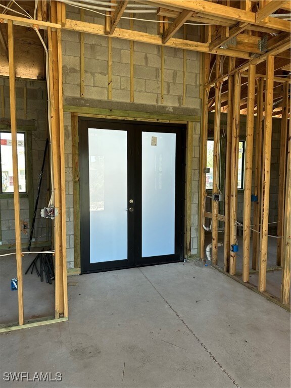 Misc room featuring french doors, unfinished concr