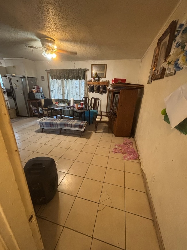Living room featuring light tile patterned floors, a textured ceiling, and ceiling fan