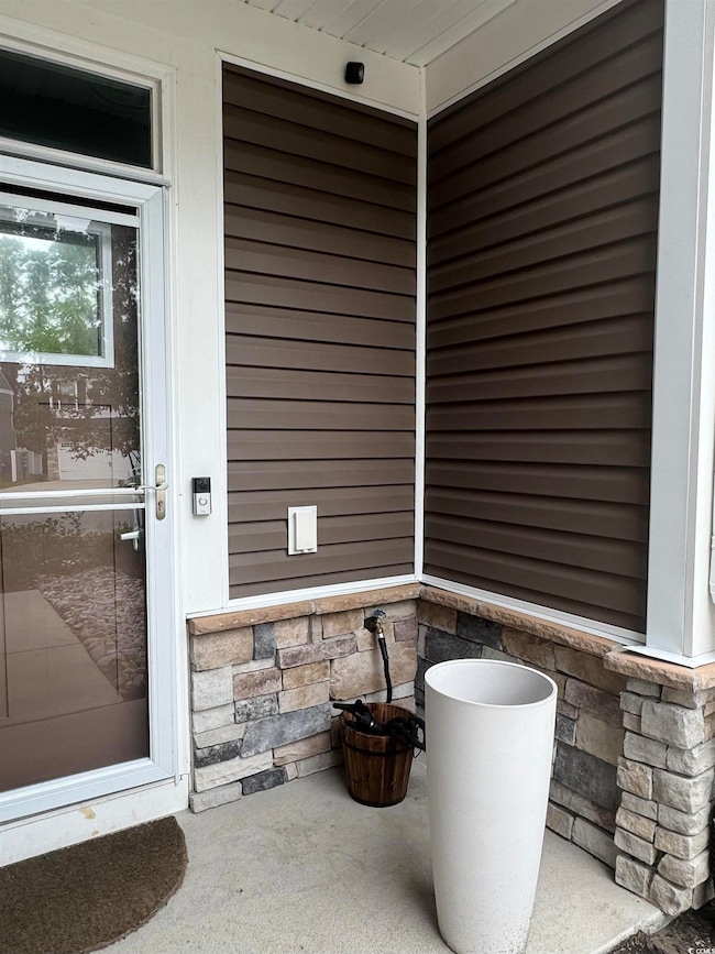 Entrance to property with stone siding and a patio