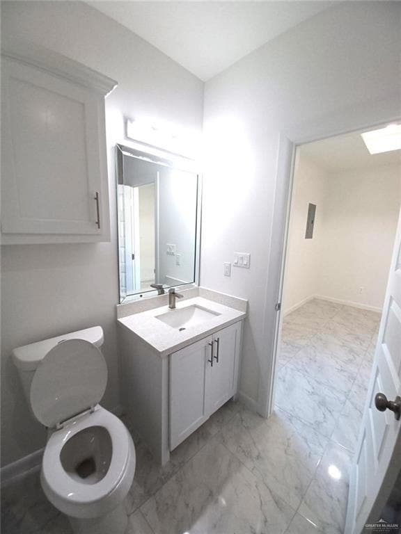 Bathroom with toilet, baseboards, marble finish floor, and vanity