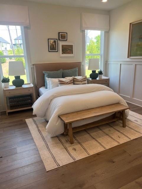 Bedroom featuring hardwood / wood-style flooring, a wainscoted wall, and a decorative wall