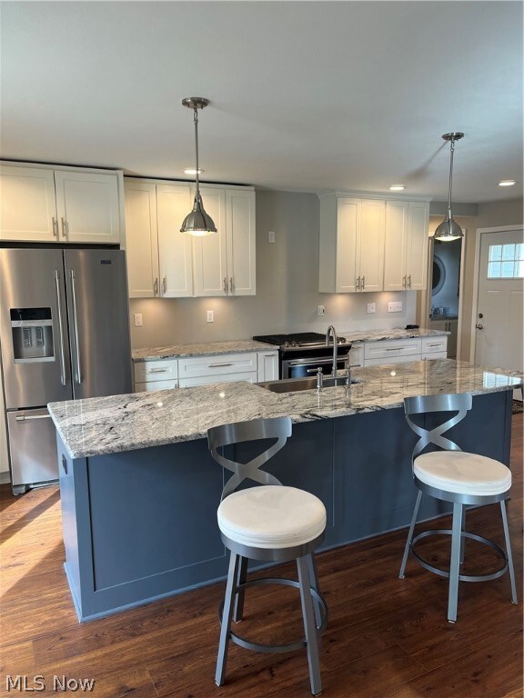 Kitchen with dark wood-type flooring, decorative light fixtures, and white cabinetry