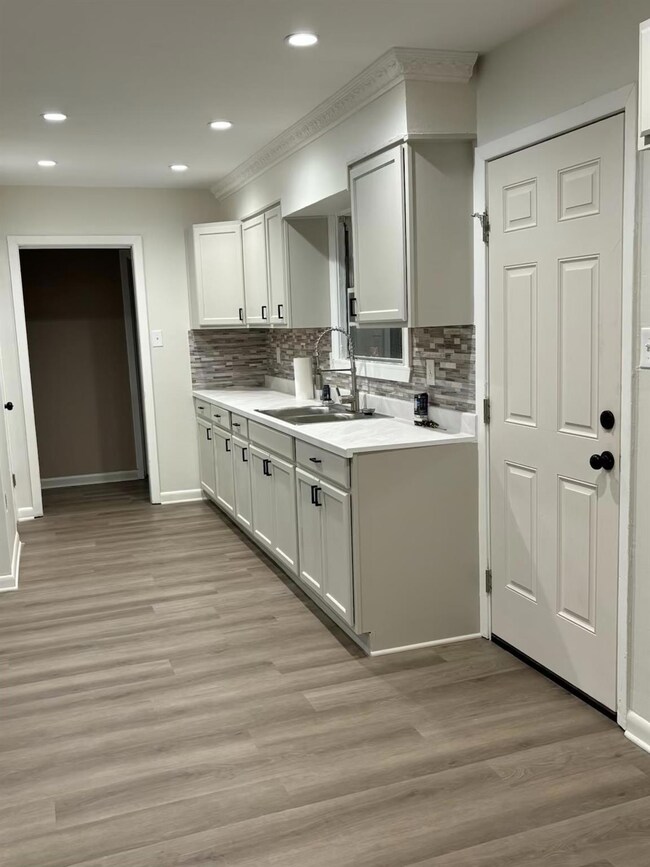 Kitchen with white cabinets, sink, light wood-type