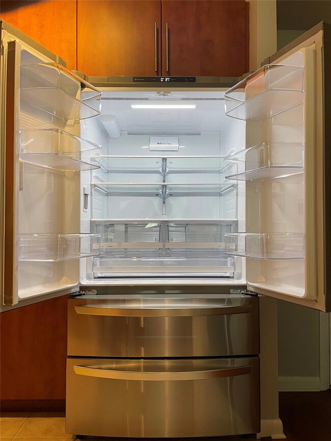 Kitchen view of stainless steel fridge, light cou