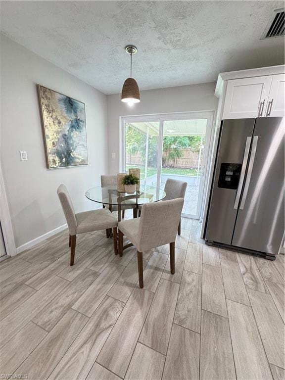 Dining area with a textured ceiling and wood finish floors