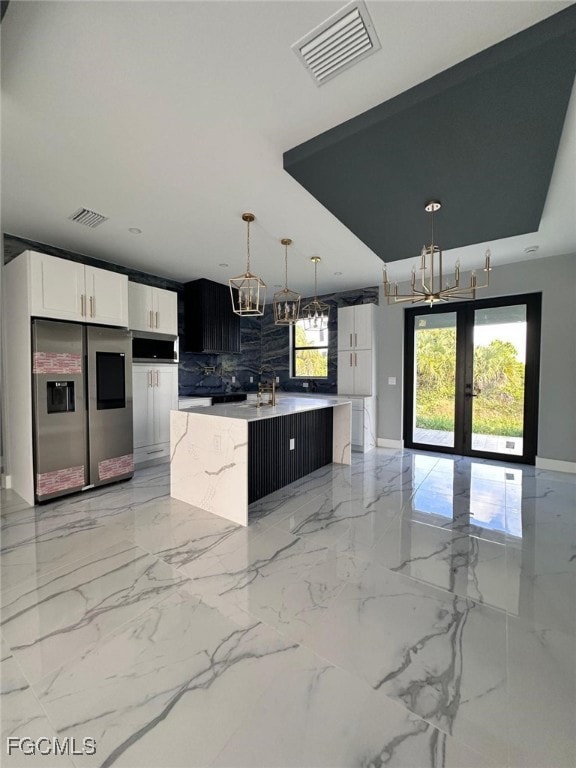 Kitchen with french doors, decorative light fixtures, a center island with sink, white cabinets, and stainless steel refrigerator with ice dispenser