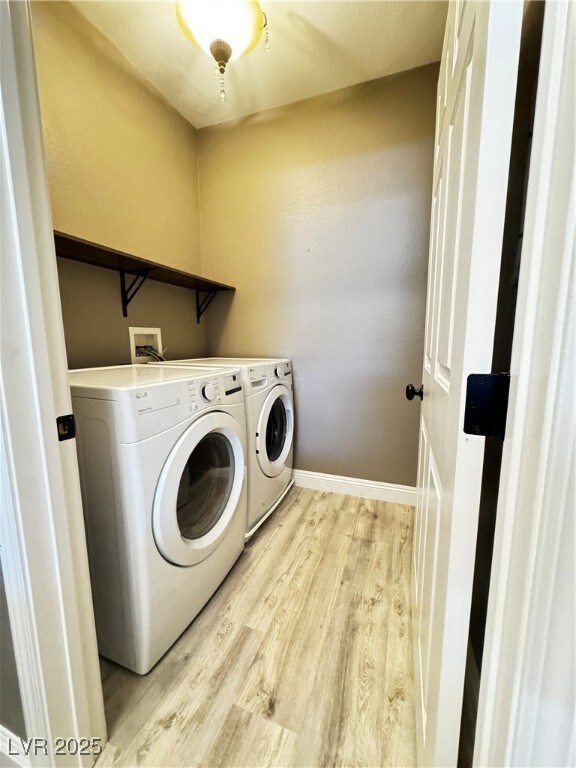 Laundry area with light wood finished floors, wash