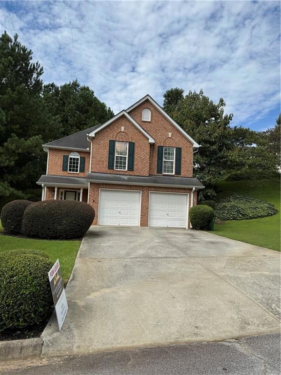 View of front facade featuring brick siding, driveway, an attached garage, and a front lawn