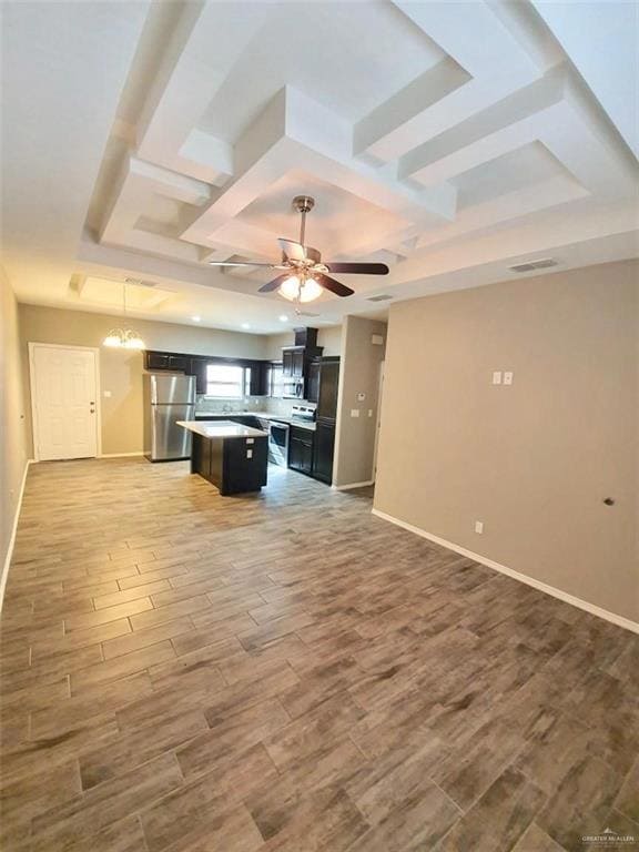 Kitchen with open floor plan, ceiling fan, stainless steel appliances, dark cabinets, and a kitchen island