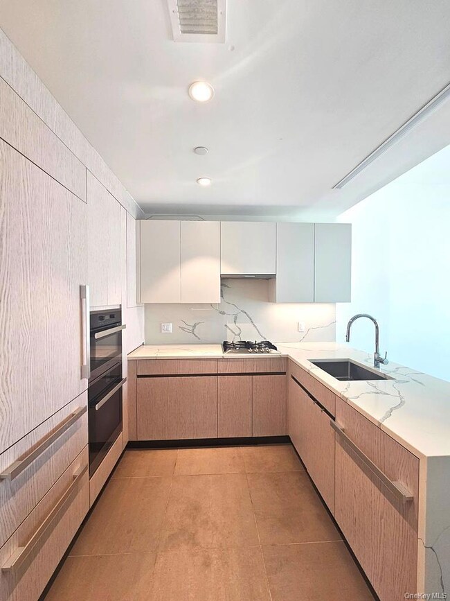 Kitchen featuring a peninsula, light brown cabinetry, modern cabinets, recessed lighting, and light stone counters