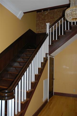 Entrance foyer with hardwood floors, and walnut hand carved handrail.