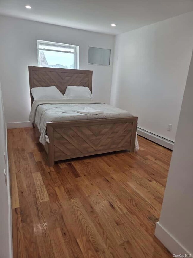 Bedroom featuring a baseboard radiator, light wood-style flooring, and recessed lighting