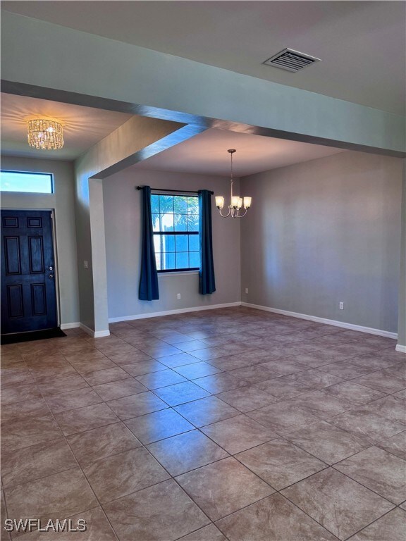 Foyer with light tile patterned floors and a chand