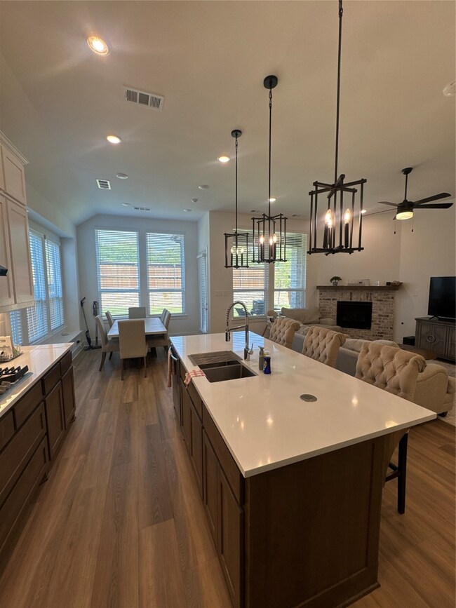 Kitchen featuring open floor plan, dark brown cabinetry, dark wood-type flooring, recessed lighting, and pendant lighting