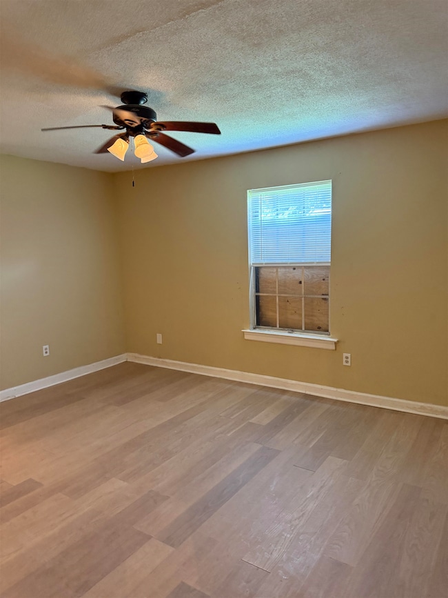 Spare room featuring wood finished floors, a textured ceiling, and ceiling fan