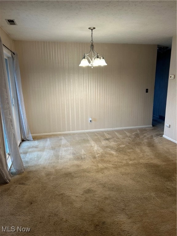 Unfurnished dining area featuring a chandelier, carpet, and a textured ceiling