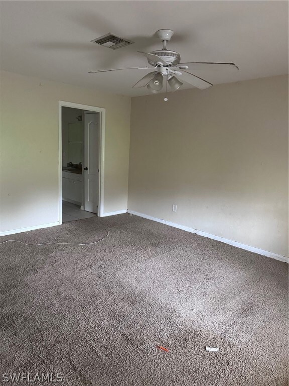 Carpeted empty room featuring ceiling fan
