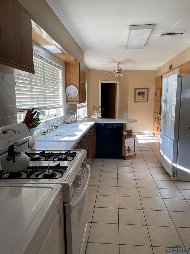 Kitchen with light tile patterned floors, white ap