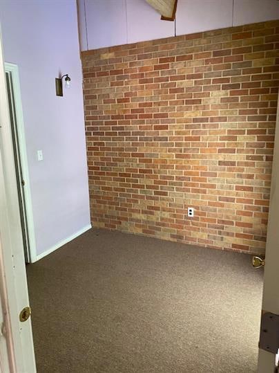 Spare room featuring carpet flooring and brick wa