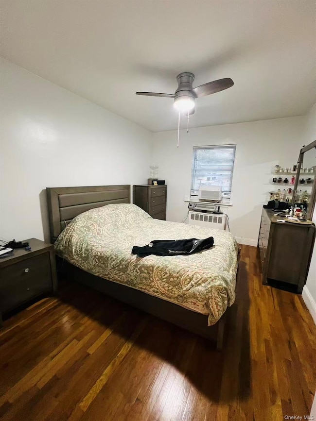 Bedroom featuring dark wood-style flooring, ceiling fan, and radiator