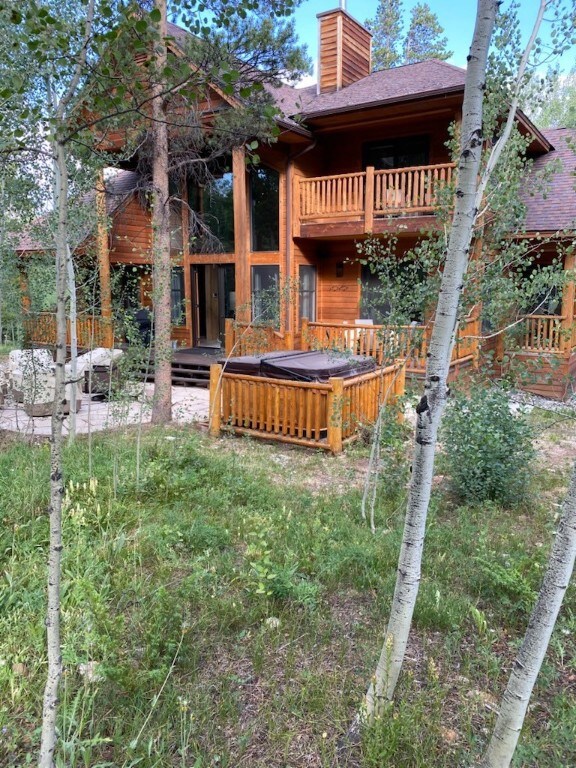 Back of property with a balcony, a chimney, roof w