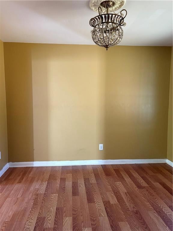 Empty room featuring wood finished floors and a chandelier