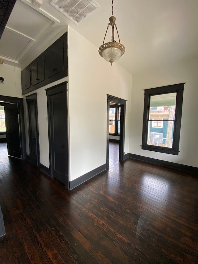 Unfurnished room featuring dark wood-style floors and attic access
