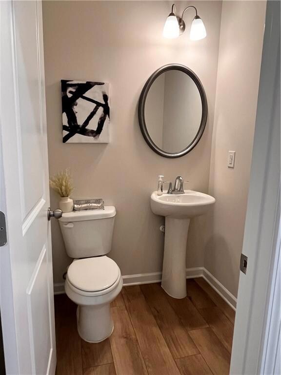 Bathroom featuring wood finished floors, baseboards, and toilet